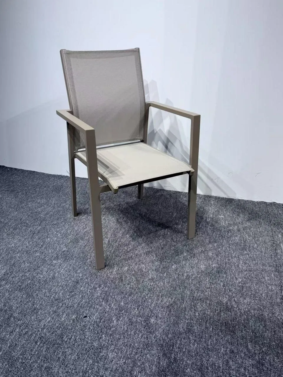 Catalogue photograph of a light sling-seat armchair with a rectangular frame, photographed on grey carpet against a white wall